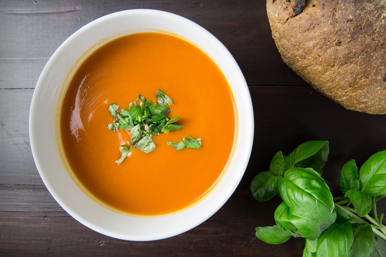 Delicious homemade tomato soup served with basil leaves and rustic bread.