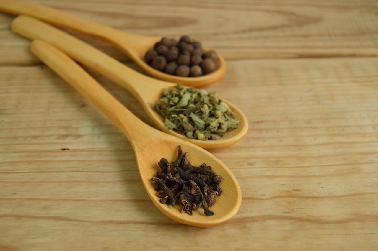Close-up of wooden spoons on a table filled with aromatic spices.